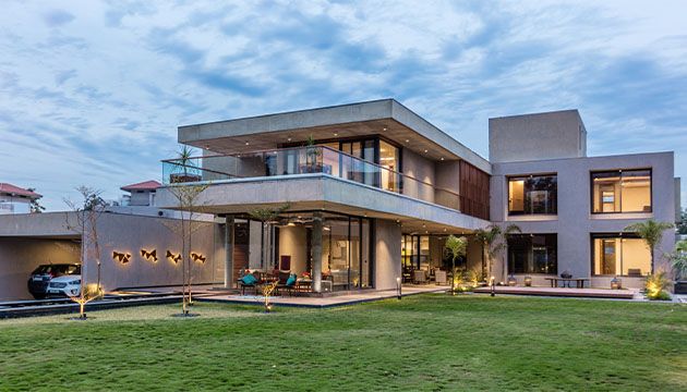 Modern residence with a wide green front lawn at dusk